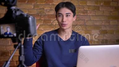 年轻的<strong>韩国</strong>男<strong>视频</strong>登记员在镜头前用手在室内打招呼的特写镜头。